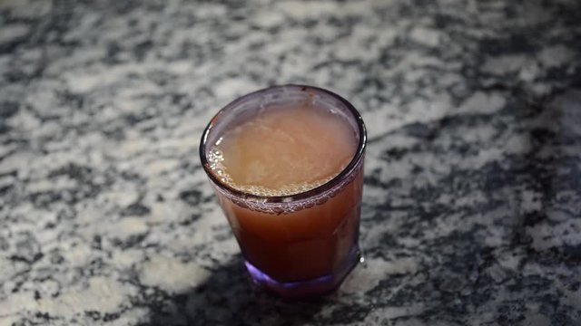 woman filling small purple cup with hot water to make instant coffee, making a small mess in the surroundings dropping water