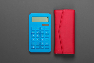 Manage family budget. Shopping costs. Blue calculator with red leather wallet on gray background. Top view