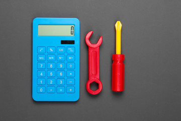 Calculation of the cost of repair work. Calculator and toy wrench and screwdriver on gray...