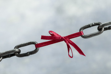 Chain tied by red ribbon, weak chain link concept on grunge background