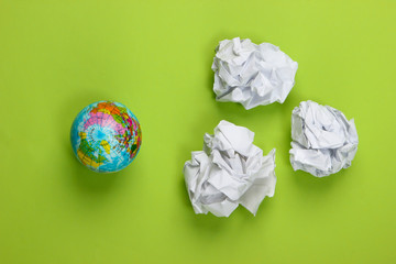 Globe with crumpled paper balls on green background. Top view. Concept art.