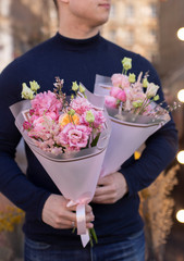 Man holding delicate bouquets of eustoma. Fresh beautiful bouquet.