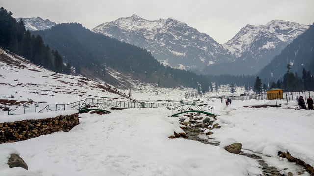 Snow landscape & glacial water stream with all snowy 
Himalaya mountains in Aru Valley, Pahalgam. Snow covered forest during Christmas/New Year holidays in Kashmir, India.