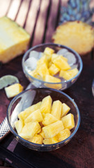 on a table two glass bowls with pieces of fresh pineapple and ice cubes