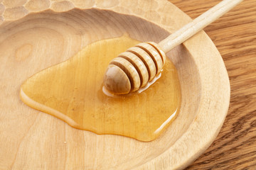 Honey dipper and fragrant honey into a wooden bowl. Healthy organic Thick honey dipping from the wooden honey spoon, closeup.  