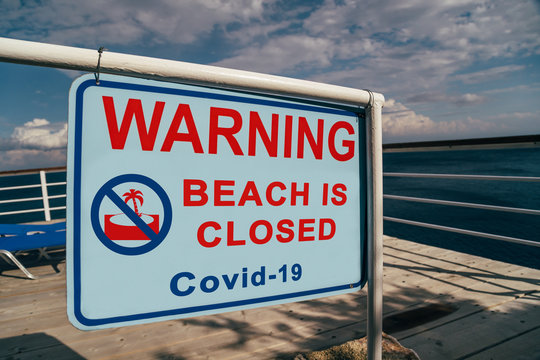 Beach is closed due to Covid-19 warning sign located at an entrance to a beach. Social media campaign for coronavirus prevention. Summer is cancelled, shutdown concept