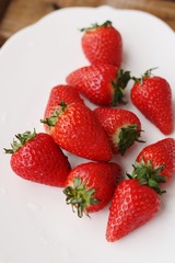 Juicy strawberries in a white plate on the table 