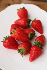 Juicy strawberries in a white plate on the table 