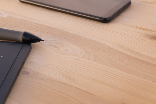 Graphic tablet and mobile black on a wooden background and copy space. Technology concept.
