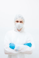 A man in a protective suit and face mask looks at the camera with his arms folded. Isolated on a white background.