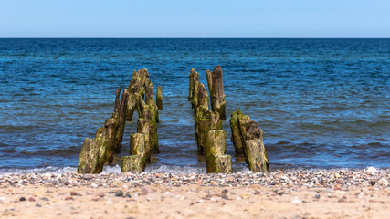 wooden breakwater on the background of calm sea and sand