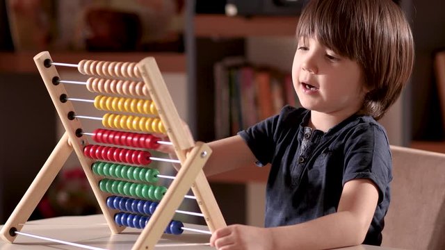Little boy working with abacus in home.