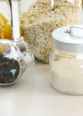 Pasta, oatmeal, pretzels, sugar and tea in glass jars on white background on kitchen.Stocks of non-perishable products. Organized home simple stylish storage no plastic, zero waste.