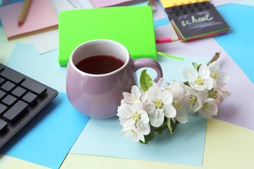 School stationery, books, cup of tea, apple tree flowers on the table, home teaching concept, part of the interior children's room, back to school
