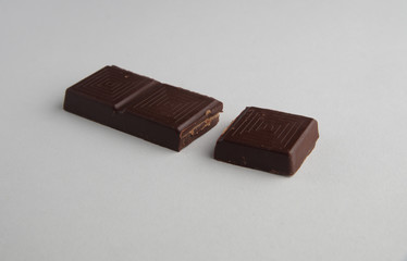 broken bar of dark chocolate on a white background