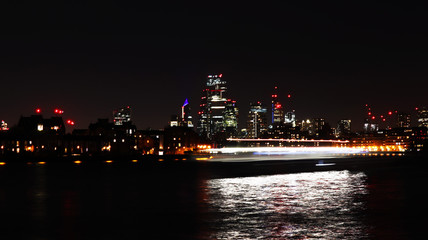 Fototapeta na wymiar Long exposure shot of London at night with tourist ship passing trough.