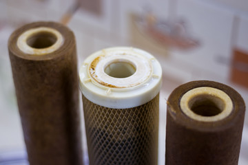Dirty used reverse osmosis system cartridges on a kitchen background. Elements of a filtration...