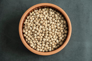 Chickpea in pot on stone, concrete background. Raw, healthy, organic and delicious cereal. Top view, flat lay.