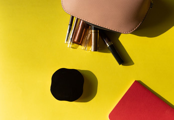 Makeup bag with various cosmetics isolated on a yellow background. Top view with side light and empty space at side. Beauty concept