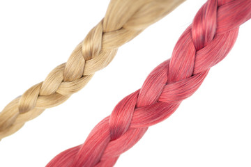 Set of tow woman fake hair extensions braided in tails, isolated on white background. Light pink and blode color with selective focus.