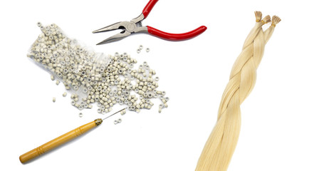 Women hair extension accessories and a fake blonde har tail braided. Pliers, tubes and a lacer, isolated on white background.