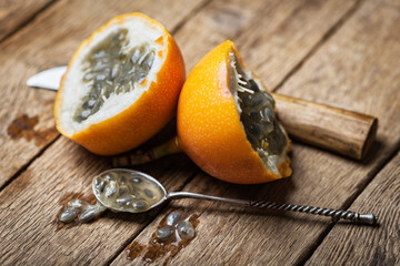 Slised passion fruit with knife and spoon on rusty wooden background. Food photography