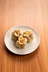 White Dish of Asian Steam  Dumplings  or Dim Sum a Famous Chinese Food  with Pork and Shrimp on  Wood Table.