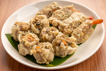 White Dish of Asian Steam  Dumplings  or Dim Sum a Famous Chinese Food  with Pork and Shrimp on  Wood Table.