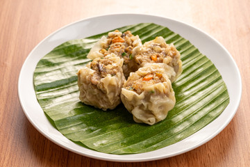 White Dish of Asian Steam  Dumplings  or Dim Sum a Famous Chinese Food  with Pork and Shrimp on  Wood Table.