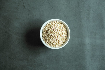 Wheat grain in white porcelain bowl on concrete, stone background. Top view, flat lay.