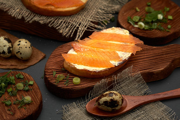 Cheese and trout sandwich on a wooden Board. Diet Breakfast sandwich with red fish, quail eggs and greens.