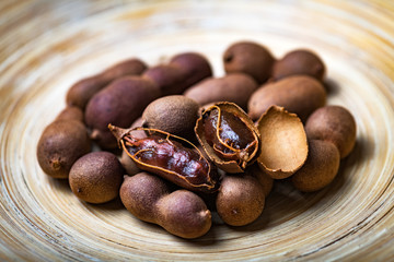Dried organic exotic tamarind fruits in bamboo bowl closeup. Studio macro shoot