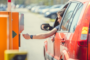 The man takes a parking ticket when entering the paid parking lot by car