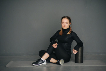 Caucasian female sportswoman uses a foam roller for relaxation, stretching muscles and back pain in workout in pilates studio. Set photo with film photo gain.
