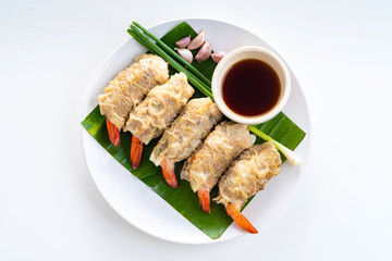 Close up Asian Steam  Dumplings  or Dim Sum a Famous Chinese Food  with Pork and Shrimp on Banana Leaf and White Dish with Garlic, Spring Onion and Peppers on White Isolated Background.