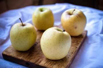 Four apples on a wooden cutting board