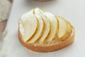 Sandwich with soft cheese and sliced pears on a white wooden table. The concept of healthy eating.