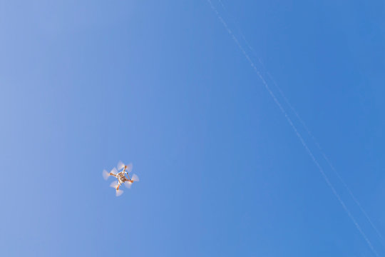 Drone copter flying in the bright blue summer sky with digital camera