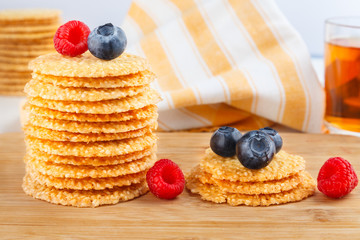 Stack of cookies with sesame seeds and fresh raspberry and blueberries on wooden board. healthy food. Close up view