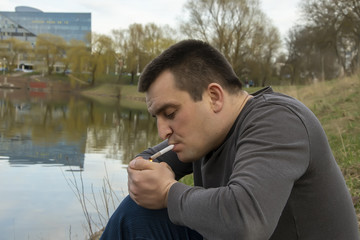 Street portrait of a man who lights a rolled joint.Concept:outdoor recreation, relaxation with the help of cannabis, avoiding problems, calming the nerves.