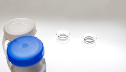 Transparent lenses on a gray background. Lenses with container. Two pairs of clear lenses on a...