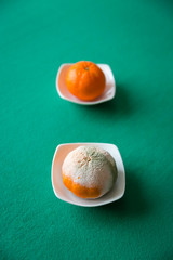 ROTTEN AND FRESH ORANGE ON WHITE DISH ON GREEN BACKGROUND