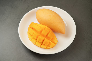Fresh Mango on white plate and black pattern background