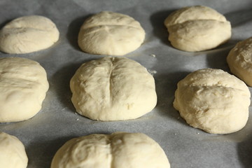 Fototapeta na wymiar Baking rolls - homemade dough formed on paper on a baking tray