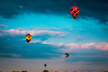 Flying hot air balloons through the sky during sunset at an airshow