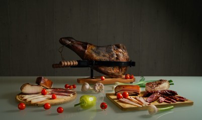 Table with pork meat delicacies, prosciutto, lard, sausage, Bavarian sausages, assorted vegetables