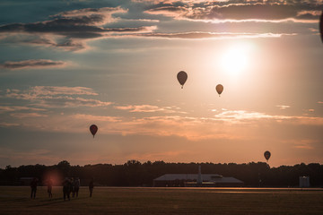 Hot air balloons floating through the air at sunset at an airshow