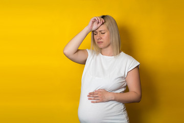 pregnant woman, blonde with a headache on a yellow background