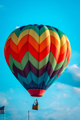 Fototapeta premium Rainbow hot air balloon flying through the sky at an airshow in Michigan
