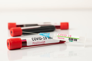 Blood test tube with positive result on Covid-19 disease with injection of coronavirus vaccine